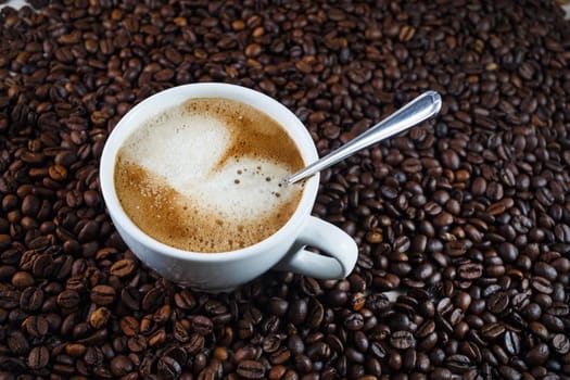 Coffee cup on coffee beans background. Selective focus.