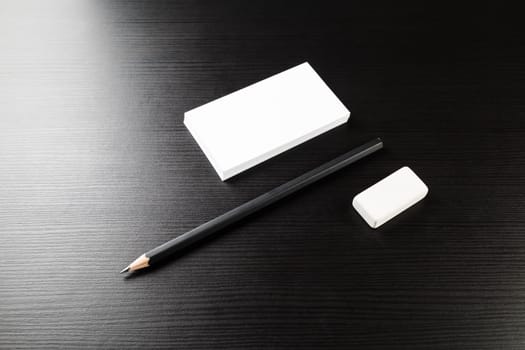 Bank business cards, pencil and eraser on black wood table background. Blank stationery template. For design presentations and portfolios. Top view.