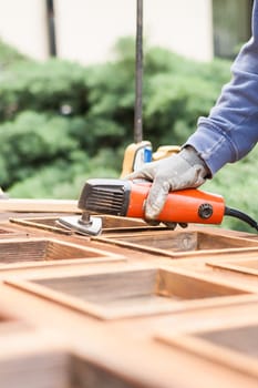Carpenter at work with angular Sander. Maintenance and restoration of an old wooden door.