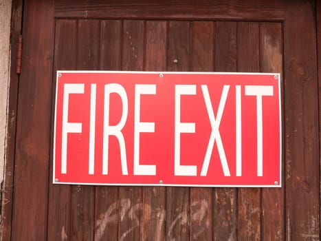 a big red and white sign outside on a fence saying fire exit