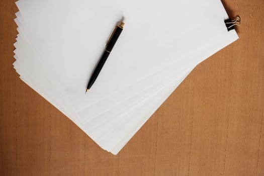 Paper and pen on the wooden table.