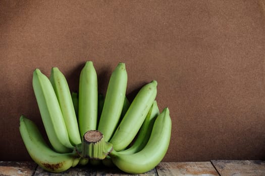 Raw green bananas on the old wood.