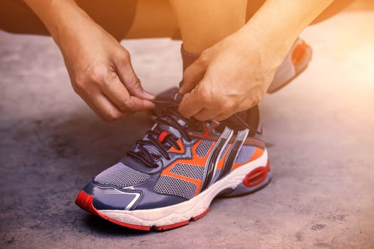 Hands tying shoes for jogging on concrete.