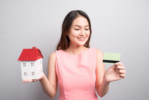Invest in real estate concept. Woman holding small toy house and credit card in hands