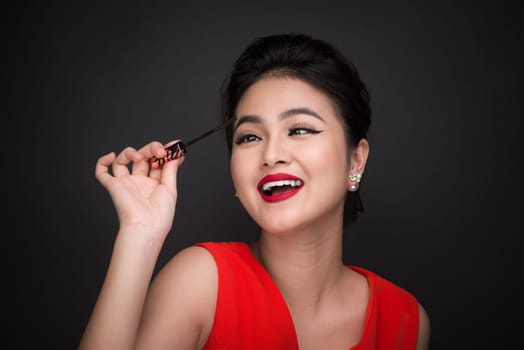 Make-up and cosmetics concept. Asian woman doing her makeup eyelashes black mascara.