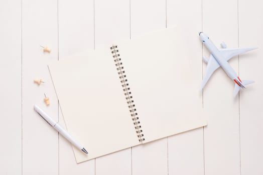 Business trip concept. Airplane and blank open notebook for your text.
