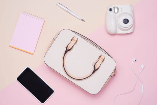 Flat lay of female fashion accessories and white handbag on pastel color background with copyspace