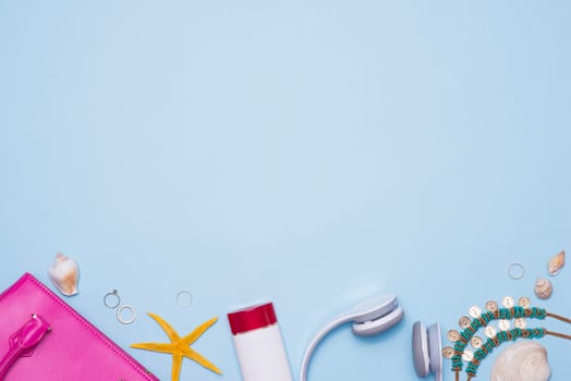Summer concept. Pink handbag with accessories on light blue background