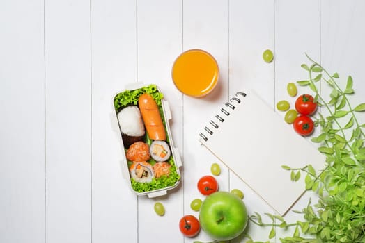 Bento box with different food, fresh veggies and fruits. Notebook with copyspace.