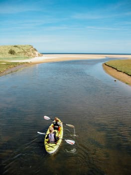 Two women are cayaking along a river in Britain.