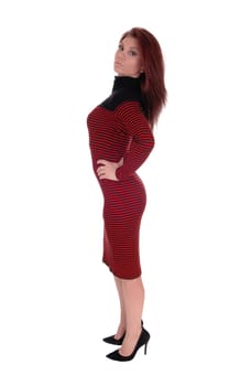 A young slim woman in a striped red and black dress standing in profile.with hands on her hip, isolated for white background..