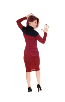 A young slim woman in a striped red and black dress standing in from .the back with her hands up, isolated for white background..