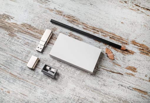 Photo of blank stationery set. Branding mockup. Bank business cards, pencil, flash drive and sharpener on vintage wood table background.