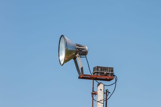 Speaker megaphone white on pole with blue sky in background