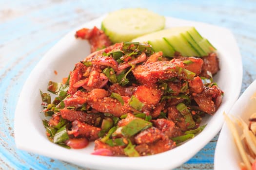 Thai cuisine spicy pork salad on wooden