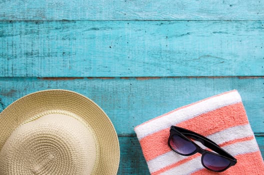 Summer holiday background. Straw hat, towel and sunglasses on blue wooden table. Top view with copy space, flat lay.