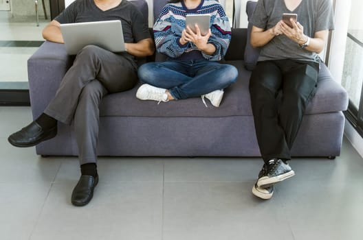 Group of friends sitting sofa using modern gadgets. Business startup friendship teamwork concept.