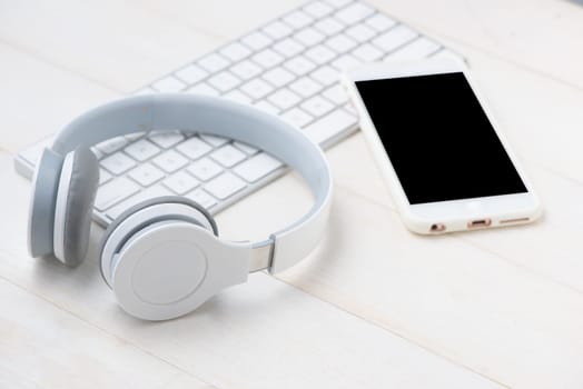 Notepad and computer keyboard on white table with headphone. View from above