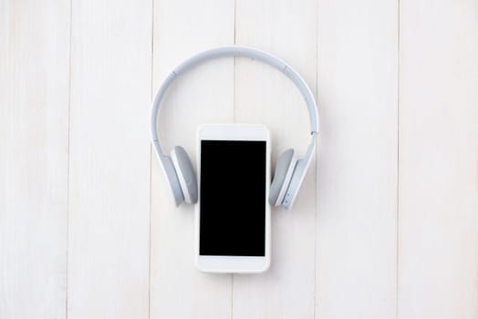 Headphone and mobile phone on white table with headphone. View from above