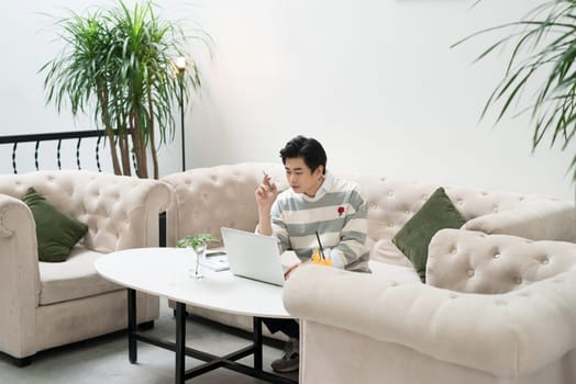 Asian young businessman working on his laptop in a coffee shop
