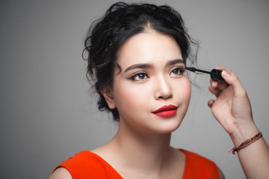 Beautiful young asian woman doing makeup using mascara on her eyelashes