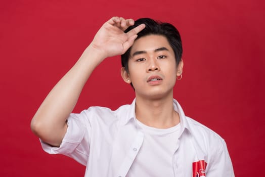 Portrait of elegant young handsome asian man over red background. Cool fashion male model.
