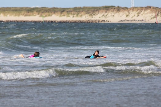 two blonde girls bathing in the sea.