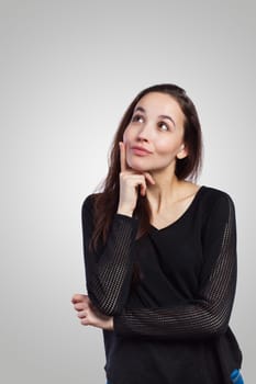 Young woman looking up at copy space, on grey background