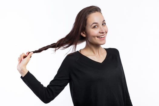 Portrait of a cute young woman pulling her hair, isolated on white