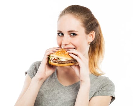 Portrait of a cute young woman biting into a burger, isolated on white