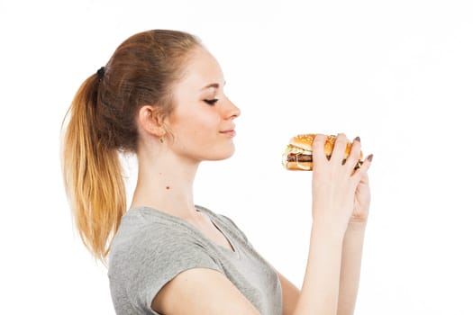 Portrait of a cute young woman with a big burger, isolated on white