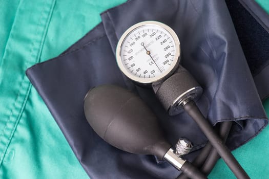 Blood pressure device located on the hospital green background. The background can be a textile part of a doctor or nurse's work uniform