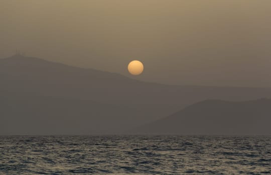 Beautiful dreamy sunset, a view through misty air from Naxos island.