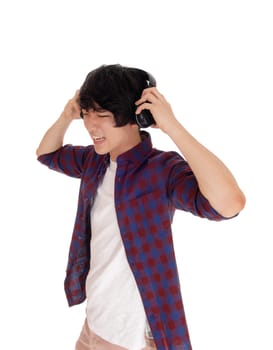 A young handsome Asian teenager listen to music with his headphone,.in a checkered shirt, isolated for white background..