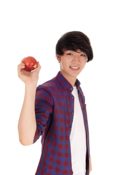 A young handsome Asian teenager in a checkered shirt holding a.red apple up and smiling, isolated for white background..