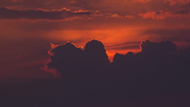Warm coloured sky before dusk, Sun sheltered behind giant cloud.