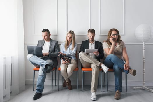 Group of young creative people sitting on chairs in waiting room