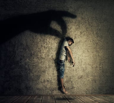 Human hand shadow holding a powerless man hanging. Conceptual image symbolizing manipulation, business control as a marionette.
