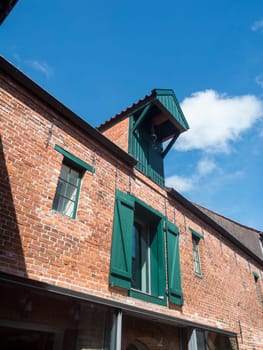 Brick façade of an old warehouse with crane in the city north before building sky with white cloud.