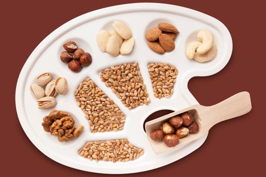Various nuts,almonds and grains on white painter's pallet freed on brown.