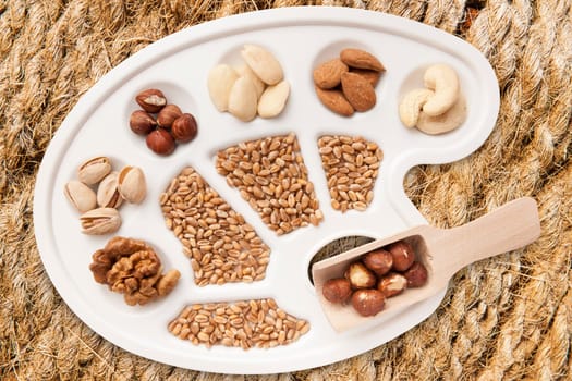 Various nuts,almonds and grains on white painter's pallet freed on sisal braid.