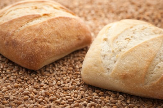 Two square rolls softly lit on spelt grains.