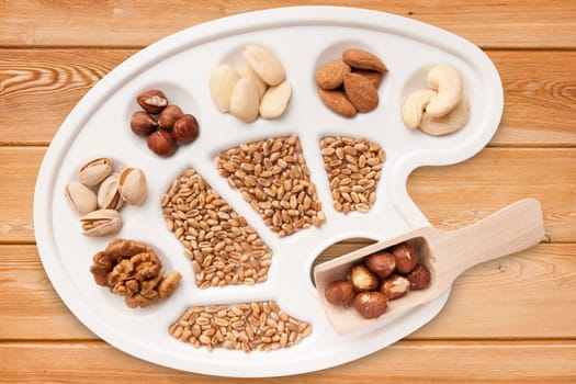 Various nuts,almonds and grains on white painter's pallet exposed on spruce boards.