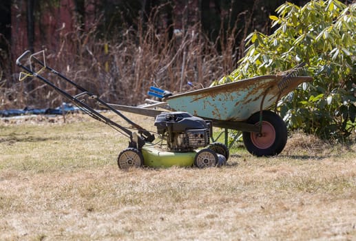 Wheelbarrow and Lawnmower in Garden.