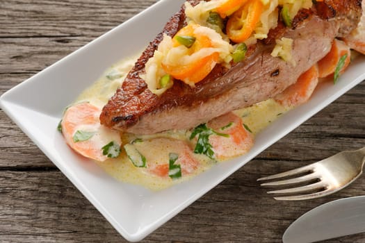 Plate with fried duck breast and kumquat and pistachio seeds on wooden table