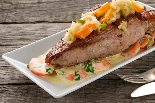Fried duck breast with carrots on a wooden plate and table