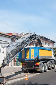 Cold planer machine loading milled asphalt into dump truck.