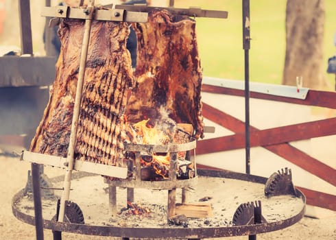 Asado, traditional barbecue dish in Argentina, roasted meat of beef cooked on a vertical grills placed around fire