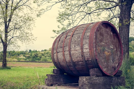 Old barrel indicating the beginning of a wine-producing area of fine grapes. Photo in vintage style.