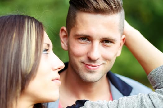portrait of happy smiling young couple in love embracing outdoor at sunny day